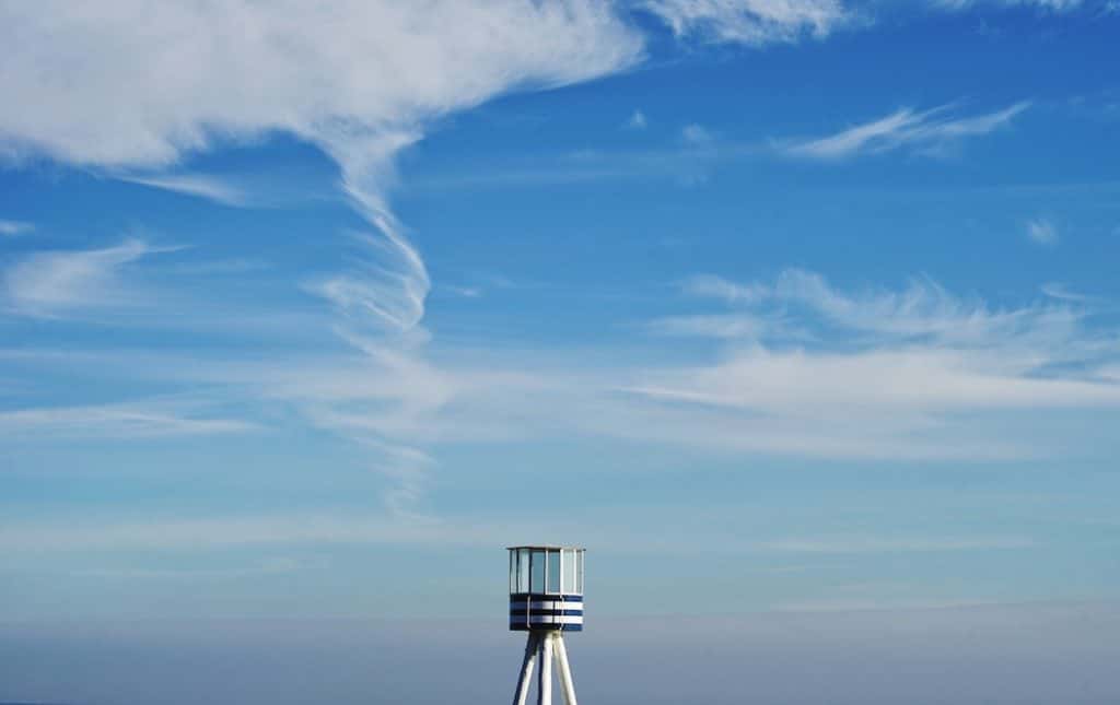 View of the top of a lighthouse against the sky with clouds